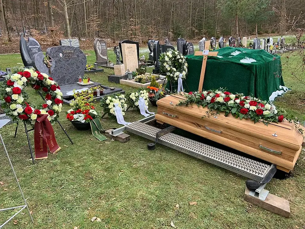 Sarg steht auf Grablegungsvorrichtung auf Rasenfl&auml;che, bereit f&uuml;r traditionelle Erdbestattung