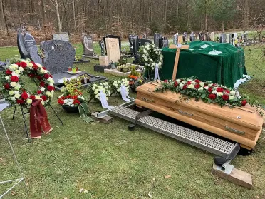 Sarg steht auf Grablegungsvorrichtung auf Rasenfl&auml;che, bereit f&uuml;r traditionelle Erdbestattung